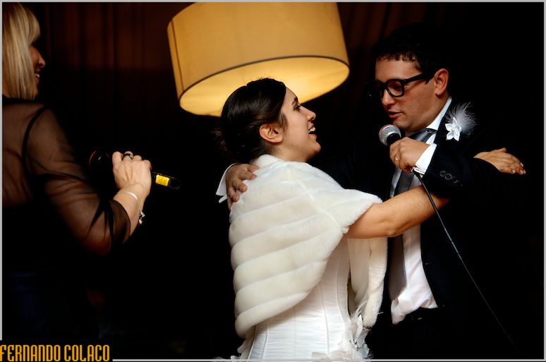 Under a round lamp, the groom sings karaoke to the bride at her wedding at Quinta da Hera.