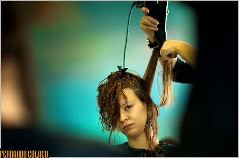 Mão da cabeleireira com um secador na mão, puxando os cabelos da noiva, no pentear.