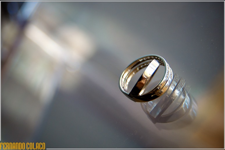 As alianças do casamento sobre vidro transparente.
