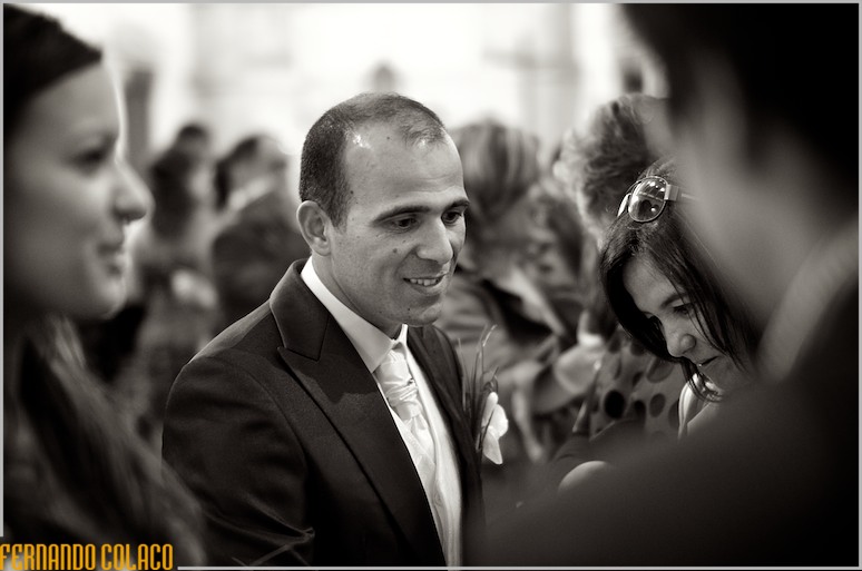 O noivo olhando para alguém, que lhe dá os parabéns pelo casamento.