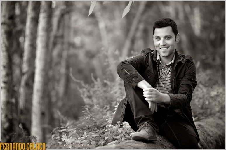 Com as árvores da serra de Sintra, o noivo, na sessão de namoro, sentado num muro antigo.