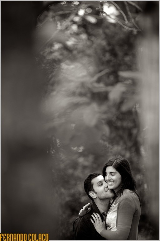 No meio das árvores do bosque em Sintra, os noivos abraçados, brincando.