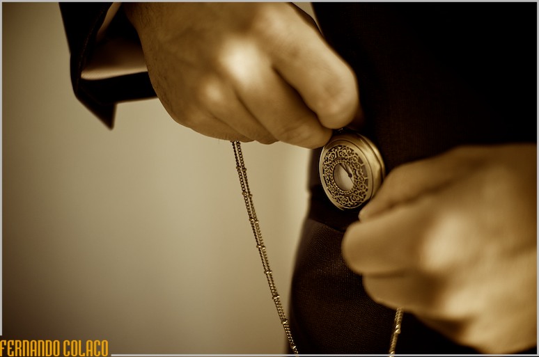 Hands of the groom putting the watch in his pocket.
