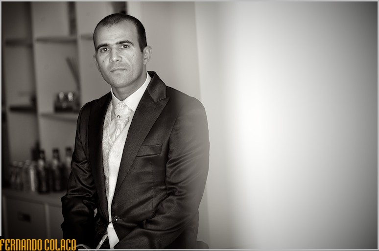 The groom, ready, sitting, in a portrait by the wedding photographer.