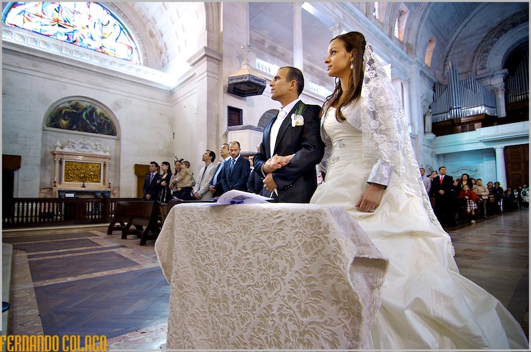 Standing, the bride and groom listen to the priest during the homily.