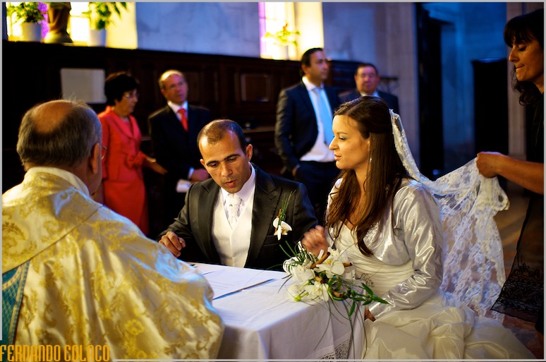 The bride and groom sitting down to sign the wedding book.