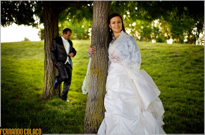 Next to two trees, the groom and the bride, standing.