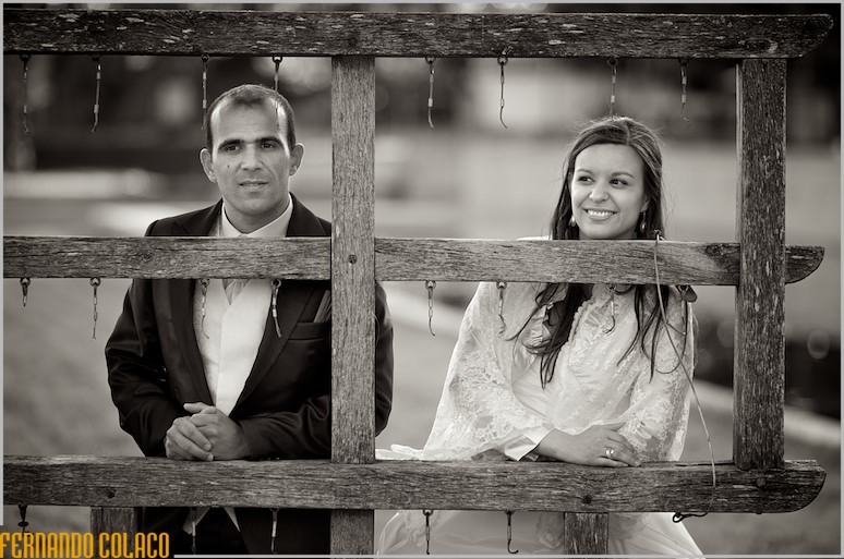 The bride and groom behind a wooden structure.