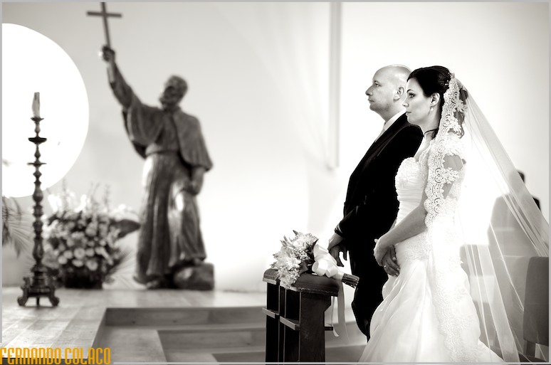 Os noivos, lado a lado, de frente ao altar, com a escultura de S. Francisco Xavier ao fundo.