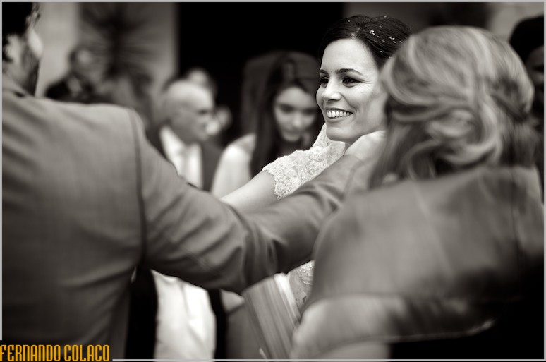 A noiva sorrindo no meio dos convidados nos cumprimentos pelo casamento.