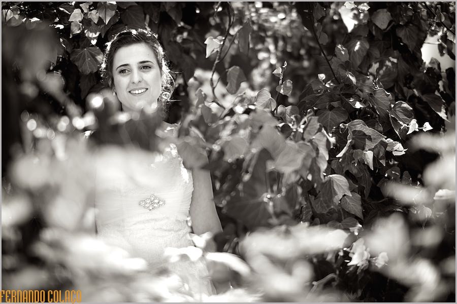 No meio das árvores do quintal da casa dos pais, a noiva sorri num retrato pelo fotógrafo de casamento.