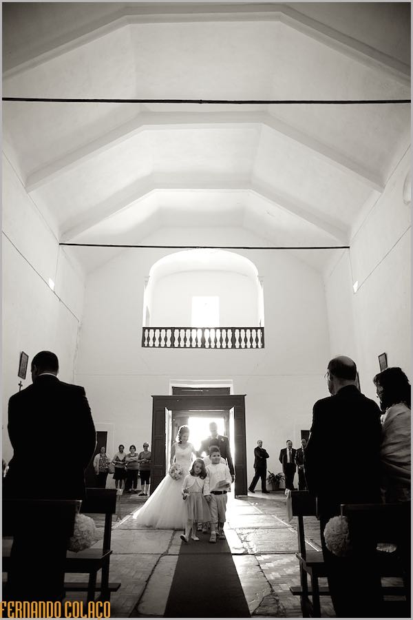 A noiva e o pai, junto de duas crianças, percorrem a igreja até ao altar, para a cerimónia do casamento.