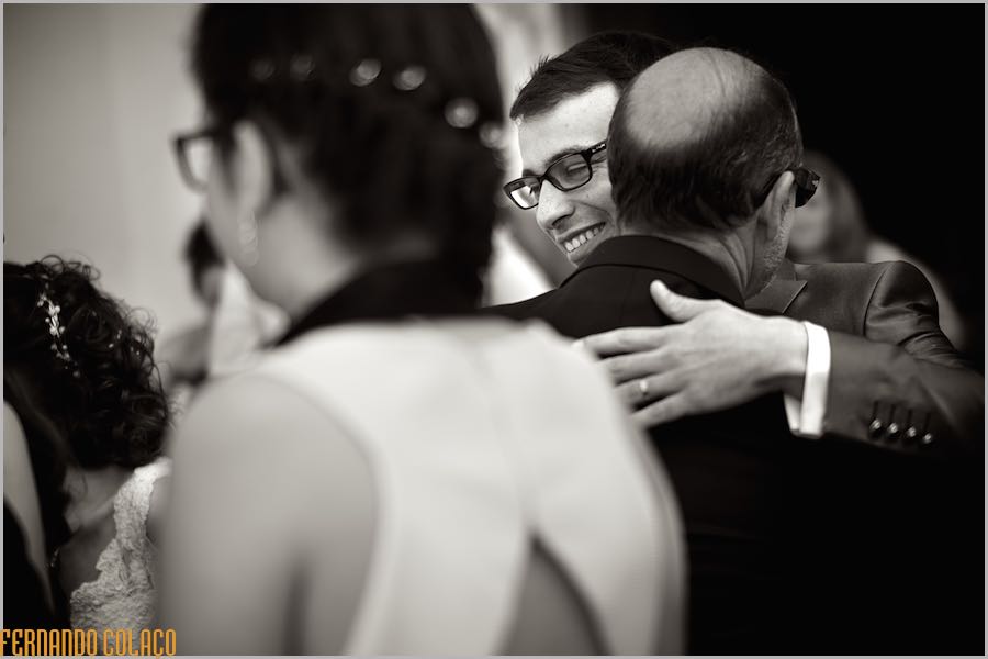 Á saída da igreja, depois da cerimónia do casamento, o noivo abraça um convidado, que o felicita.