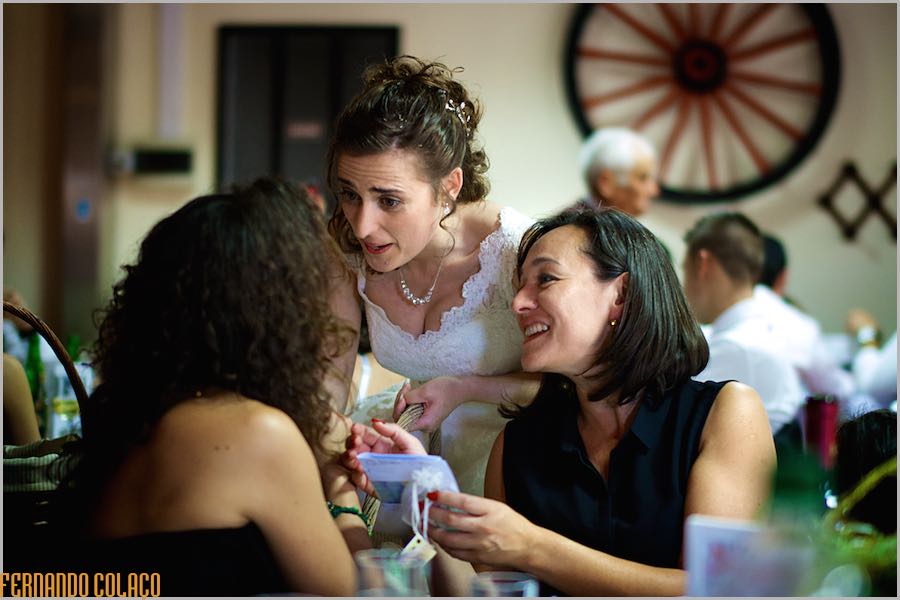 A noiva conversa com duas convidadas quando lhe entrega prendas, durante a festa do casamento.