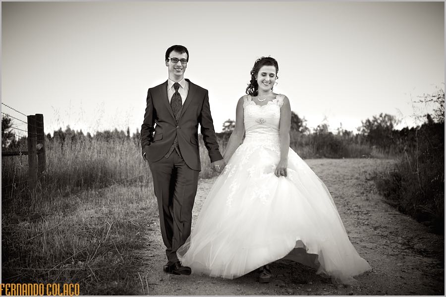 De mãos dadas, o casal de recém casados desce a estrada campestre, na sessão com o fotógrafo de casamento.