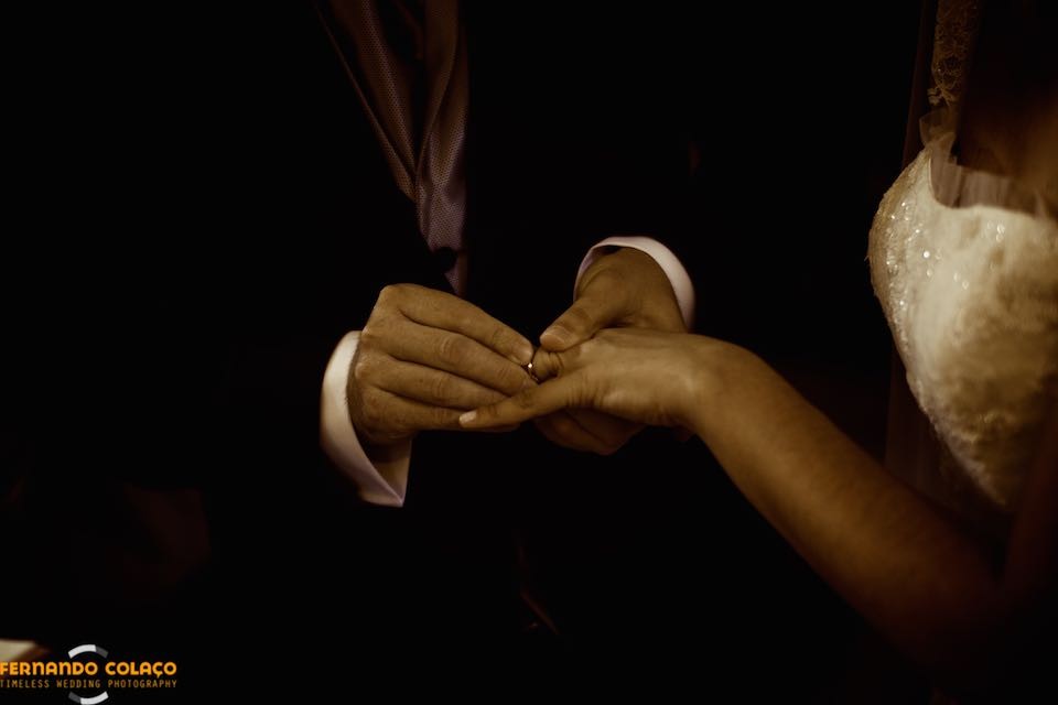 Pormenor das mãos dos noivos, quando o noivo põe a aliança no dedo da noiva.