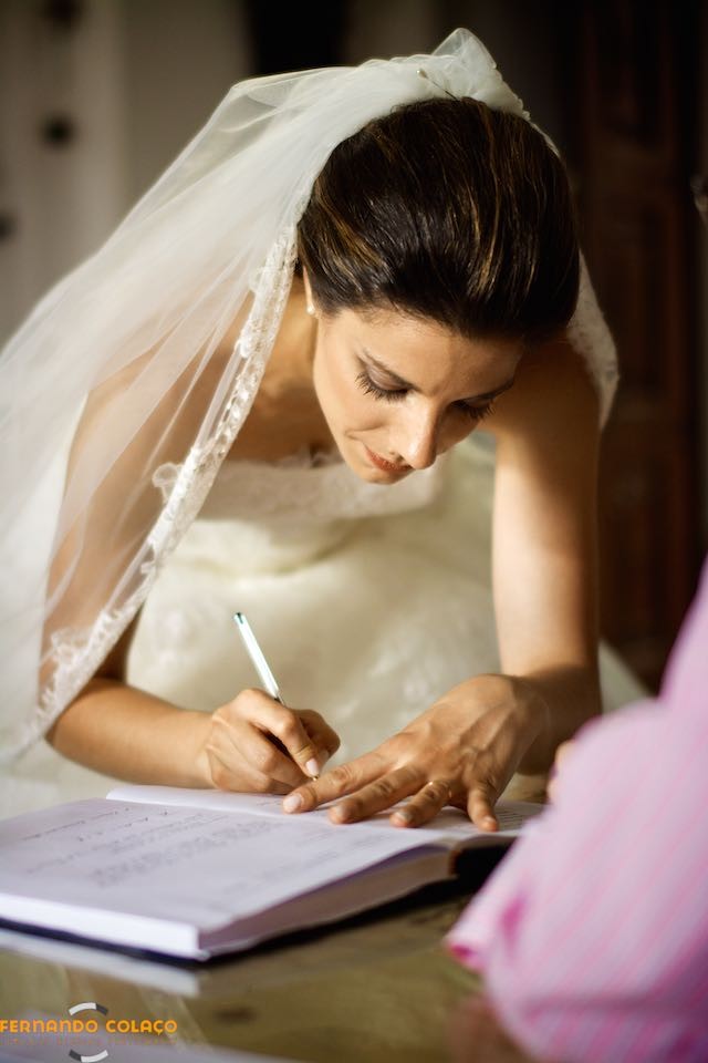 A noiva assina o livro do casamento.