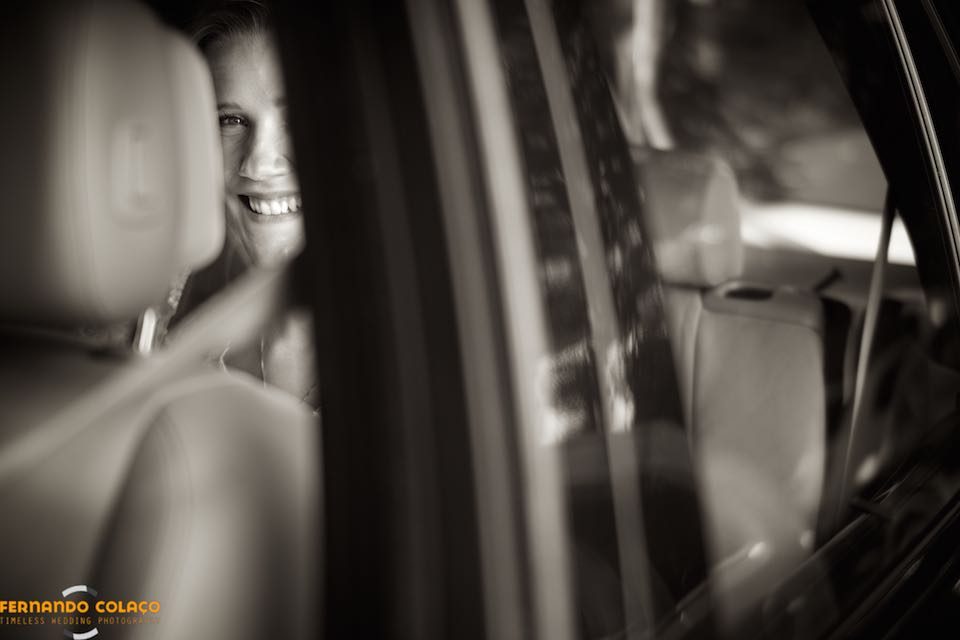 The bride's face appears partially through the window of the car that will take her to the place of the wedding party.