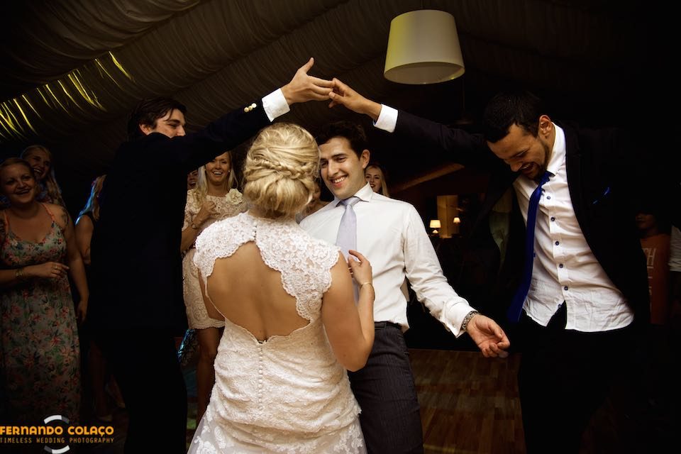 The bride and groom, during the wedding party, dance under the arms of two guests, who simulate an arch