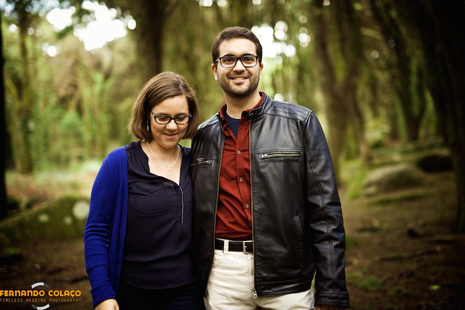 With the trees, from the Peninha forest in Sintra, green behind, the bride and groom walk hugging each other.