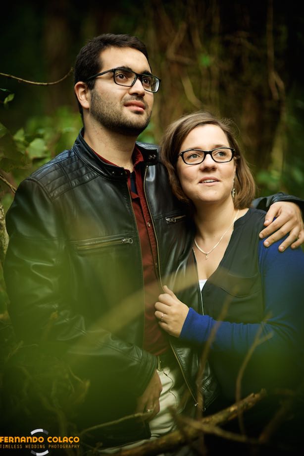Amidst the green of the plants of the Sintra mountains, the groom embraces the bride and, together, they comment on something far from them.