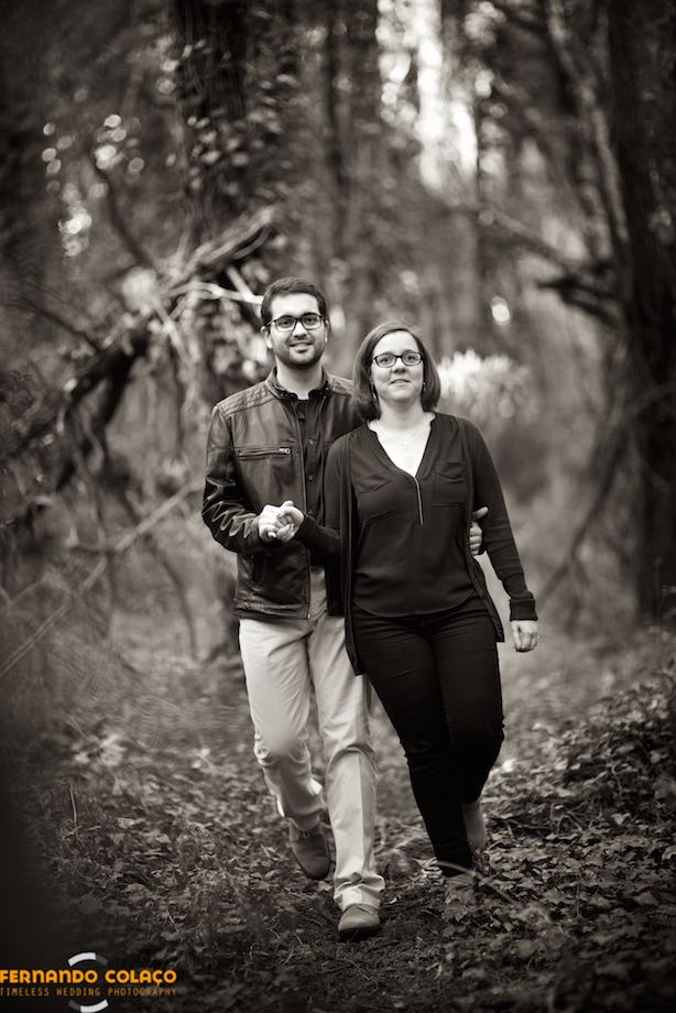 The bride and groom walk along a path in the woods of the Serra de Sintra, in the middle of the trees.