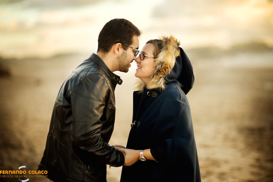 The newlyweds, in profile, rub their noses like Eskimos, in the golden sunset on Guincho beach in Cascais.