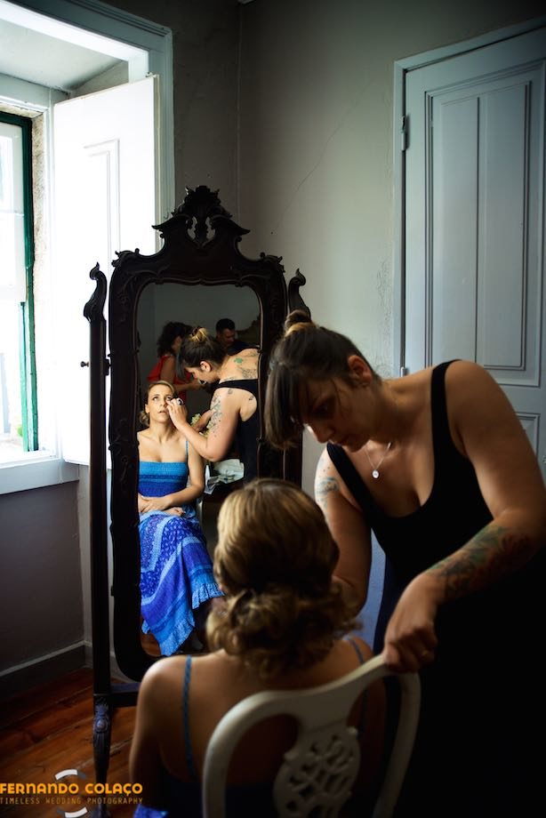 Noiva e maquilhadora num espelho em processo de maquilhagem.