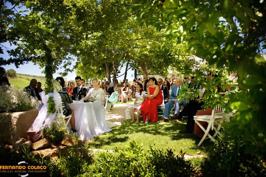 Emoldurados pelas árvores da Quinta da Taipa em Alenquer, os noivos na mesa da cerimónia do casamento com alguns dos convidados.