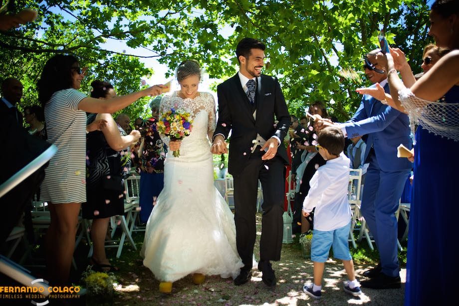 Depois da cerimónia do casamento, os noivos, de mão dada, percorrem a saída entre os convidados que os aclamam.