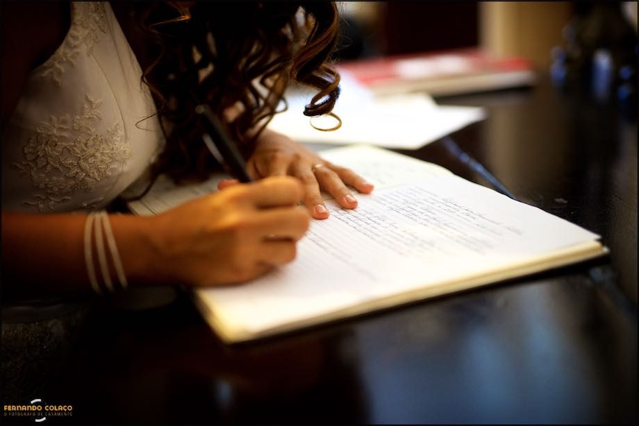 Mãos da noiva enquanto assina o documento do casamento.