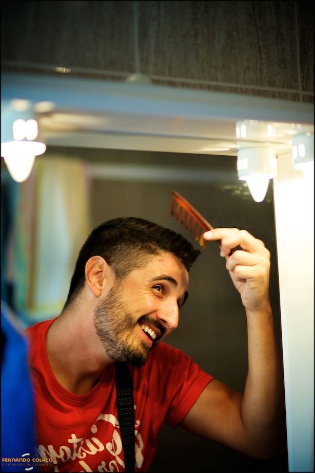 Groom combs his hair in front of the mirror.