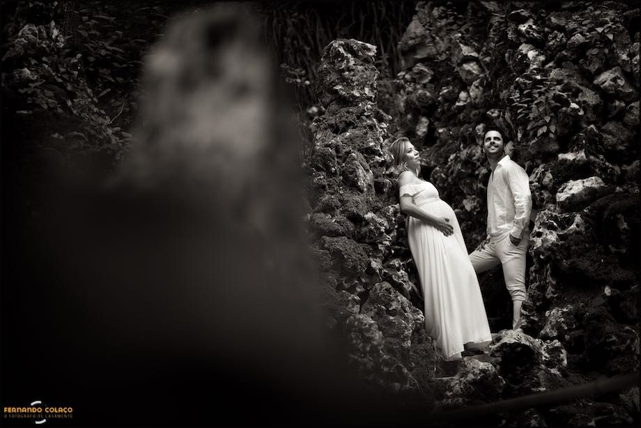 O casal encostados à paredes rugosas do jardim.