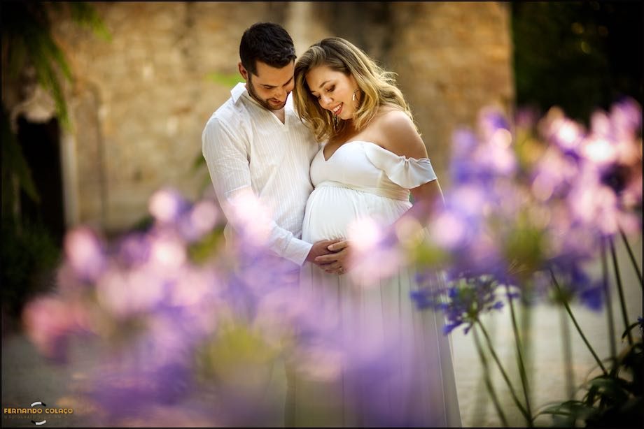 O marido faz uma festa na barriga da sua mulher grávida envoltos em flores.