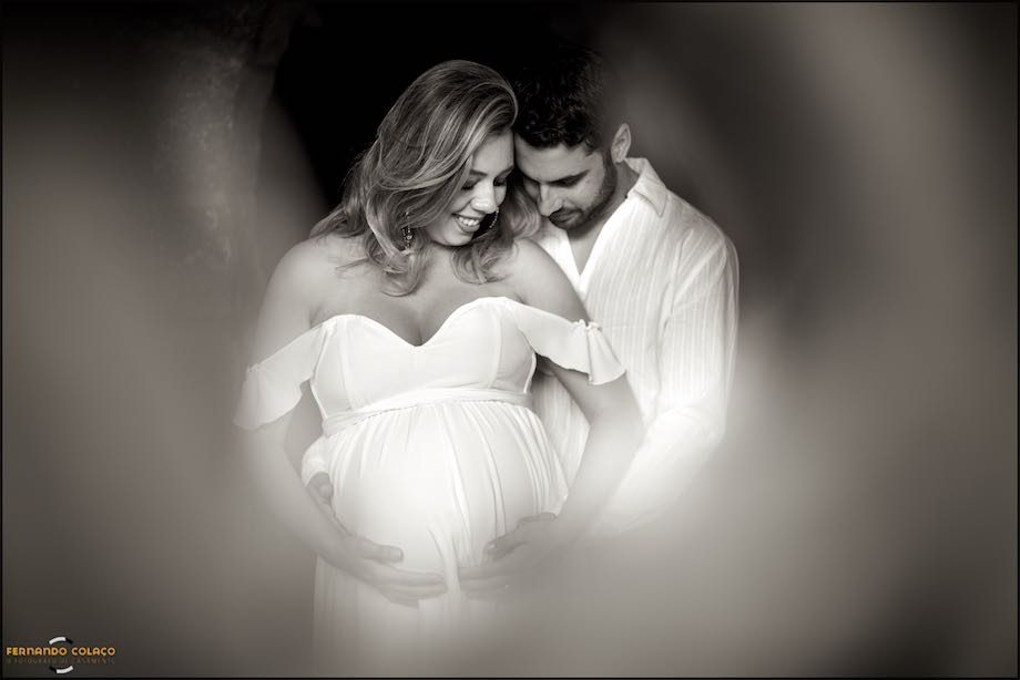 Grávida segura  a barriga enquanto o marido olha junto a ela.