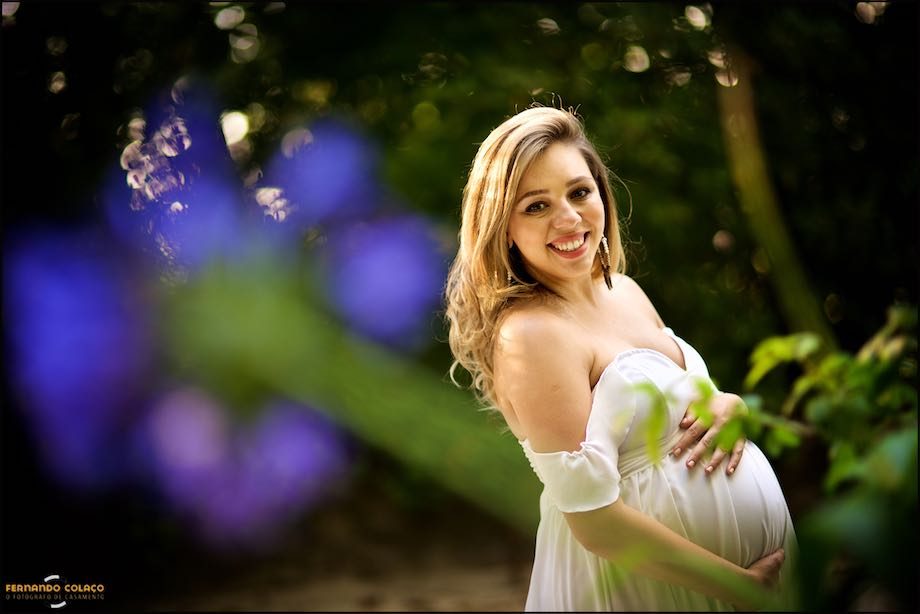 Grávida sorri com agapanto azul desfocado.