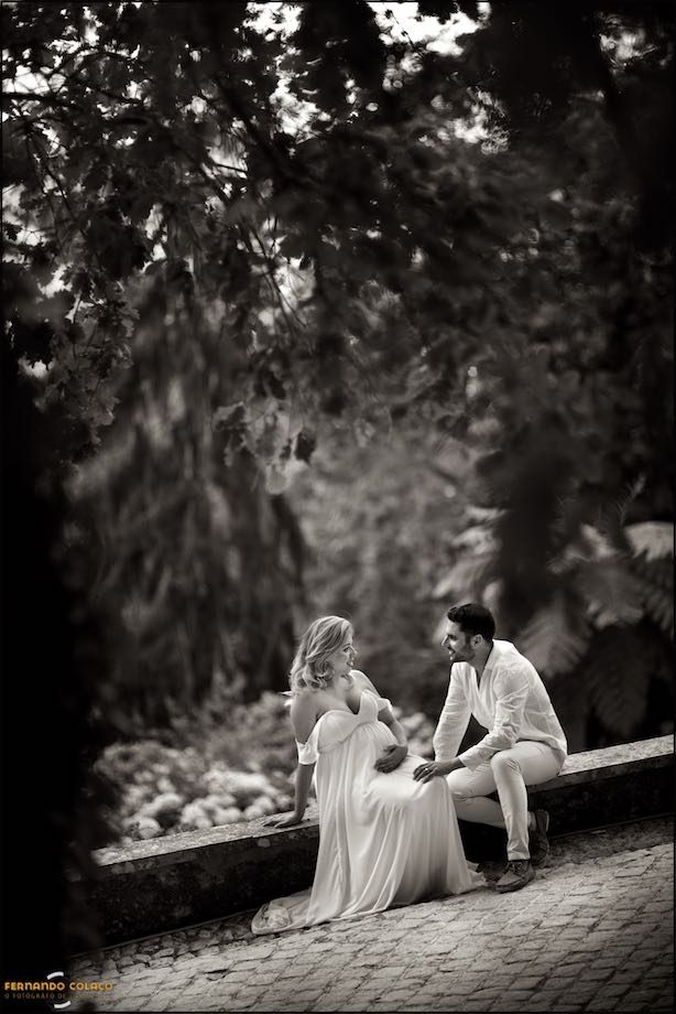 Sentado no muro com a floresta do jardim por fundo.