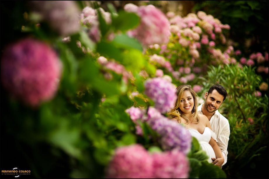 O casal por entre flores de tons rosa.