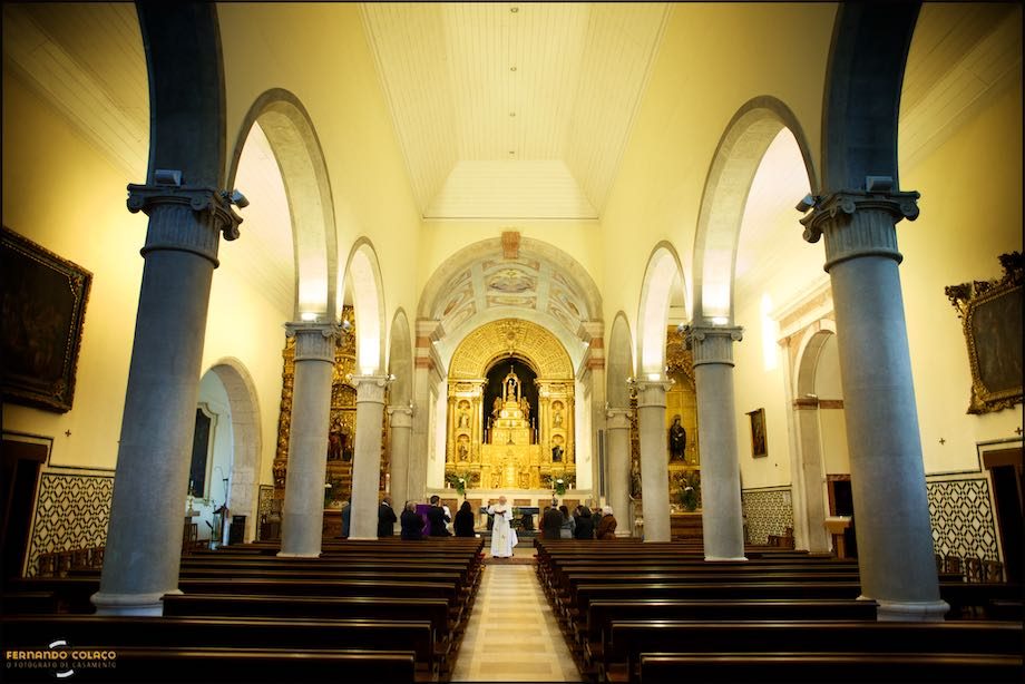 Vista geral da igreja com altar ao fundo e família no ritual do batismo.