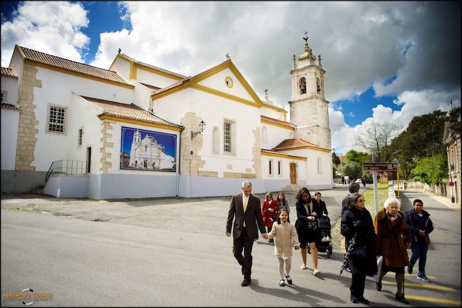 Familia, com a Igreja de São João do Lumiar ao fundo, caminham para o local da festa do batizado.