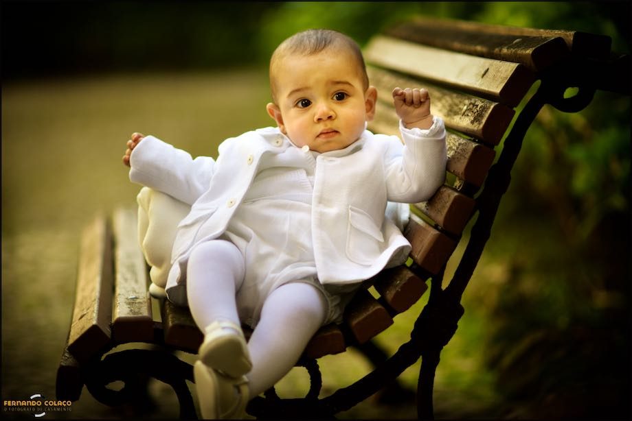 Menino, ainda bebé, sentado num banco de jardim.