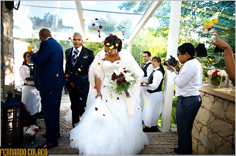 Os noivos entram no local da festa do casamento na Quinta do Roseiral, sob pétalas de flores amarelas e vermelhas.