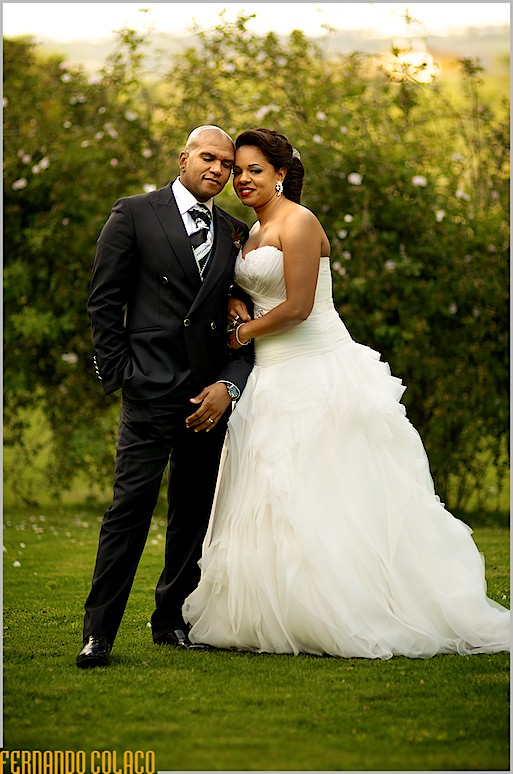 Numa pose para o fotógrafo de casamento, o casal de recém casados, de pé, de rostos juntos.