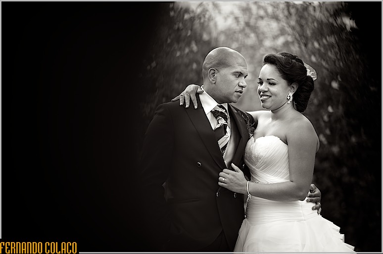 Num retrato a preto e branco, pelo fotógrafo de casamento, a noiva abraça o noivo pelo pescoço, enquanto olham um para o outro.