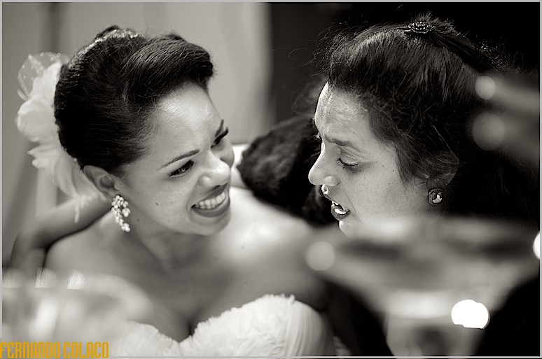 Uma convidada do casamento conversa com a noiva, que a ouve sorrindo.