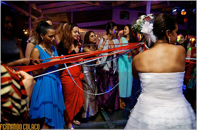 A noiva com as fitas seguradas pelas solteiras no casamento.