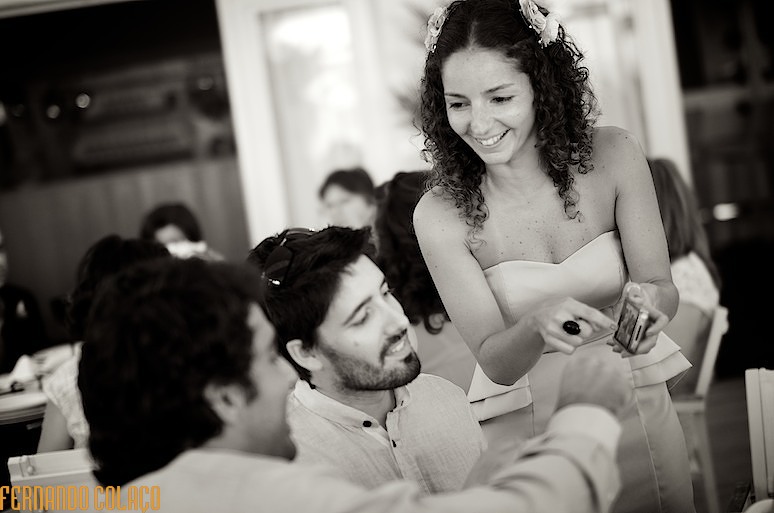 Convidada do casamento mostra uma fotografia, no telemóvel, a dois amigos.
