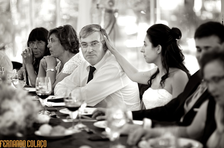Noiva faz uma festa nos cabelos do seu pai, na mesa da refeição do casamento.