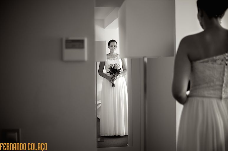 A noiva, de costas e desfocada, olha para si, reflectida num espelho e pronta para partir para a cerimónia do casamento.