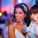 Girl, on the bride's lap, makes soap bubbles the wedding party in Wakiki in Praia da Sereia, by the wedding photographer.